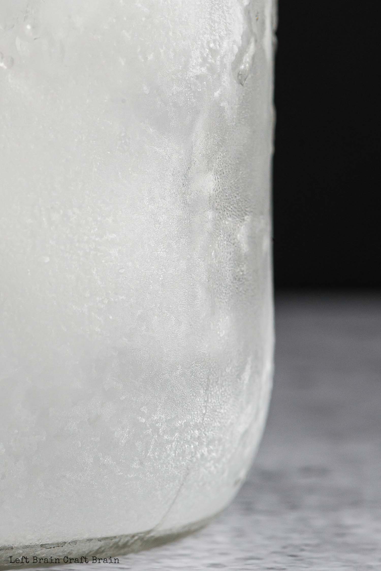 closeup of ice in jar on black background with frost on the side