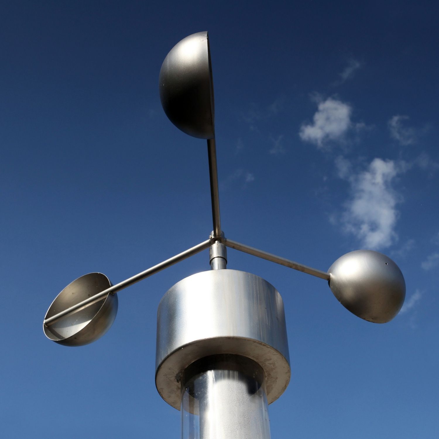 anemometer wind speed measuring device in blue sky with fluffy clouds