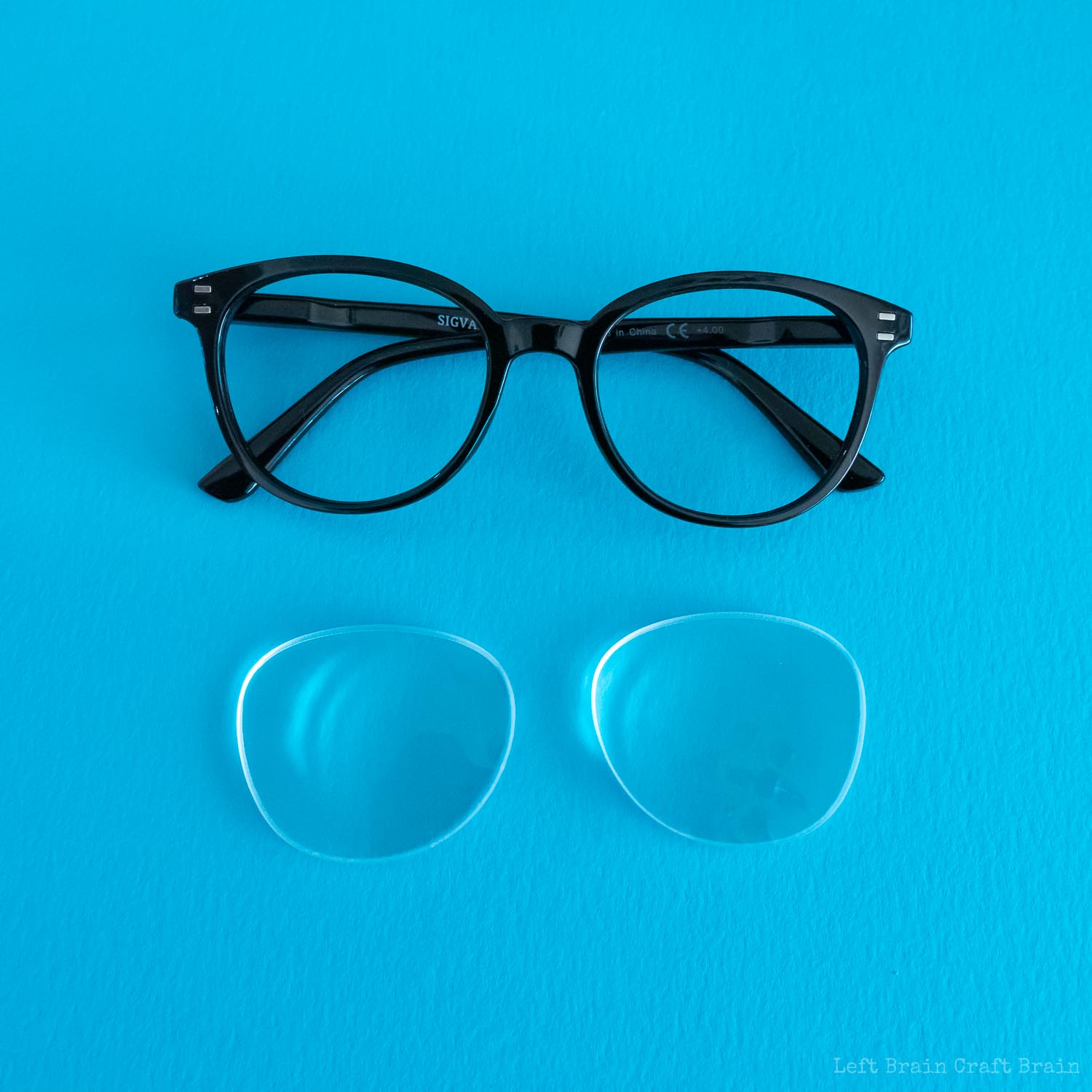 how to make a telescope - black eyeglasses on blue with lenses removed and laying underneath