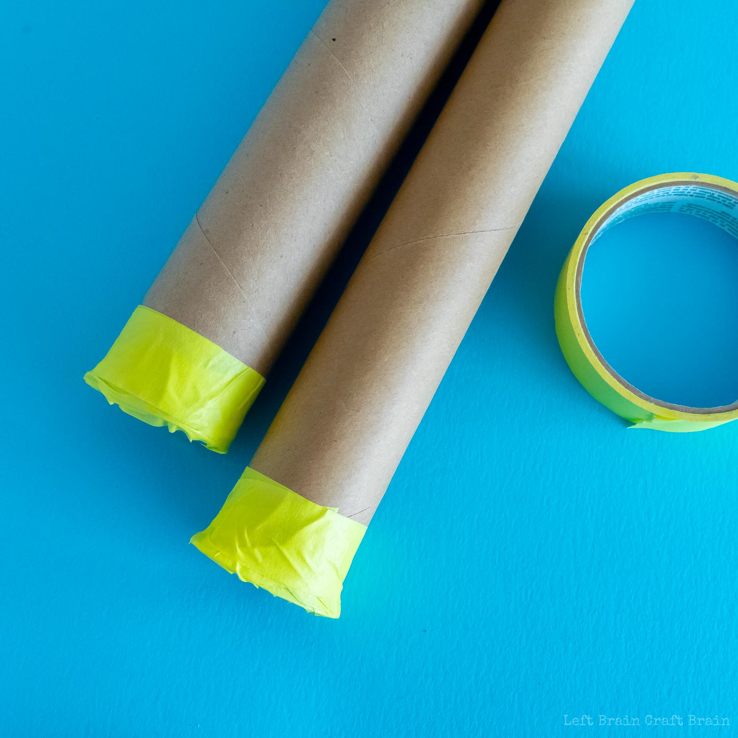 diy telescope - two paper towel rolls with ends taped with yellow tape plus yellow tape roll on blue paper